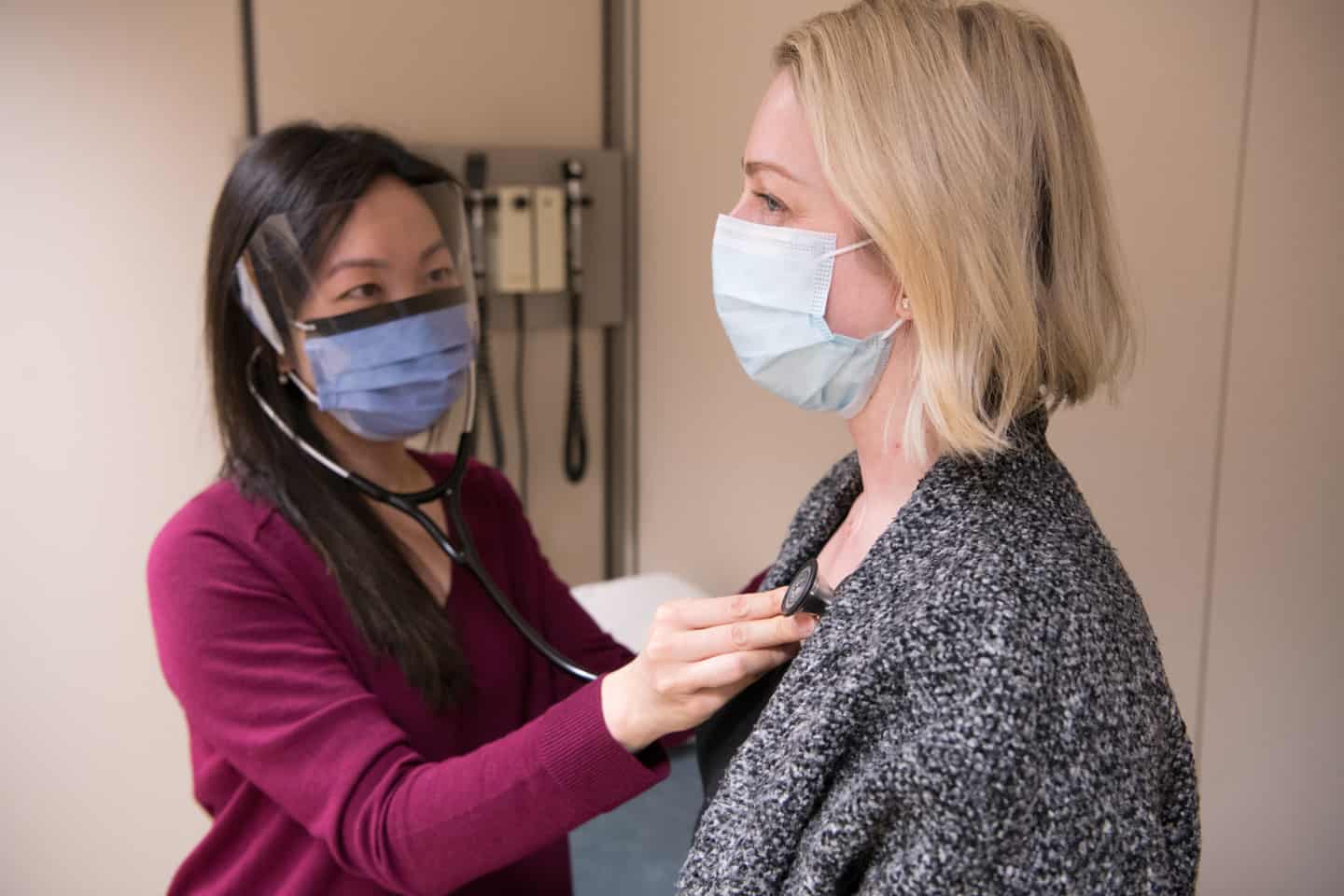 Image of A doctor wearing a mask examines a masked patient with a statoscope