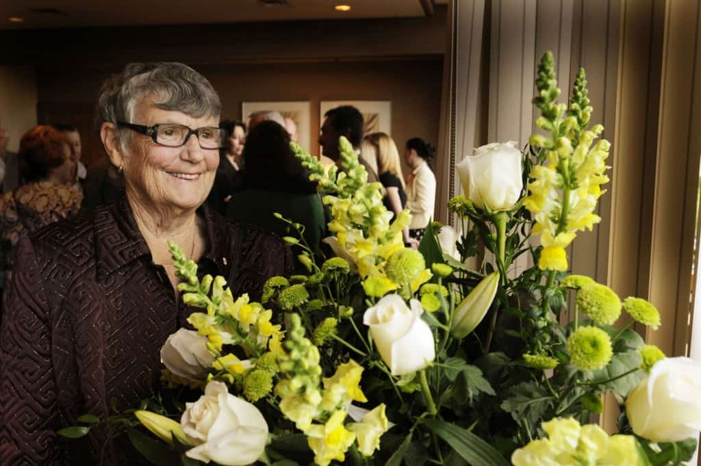 Image of Patricia Mathilda “Pat” Proudfoot standing by a floral bouquet