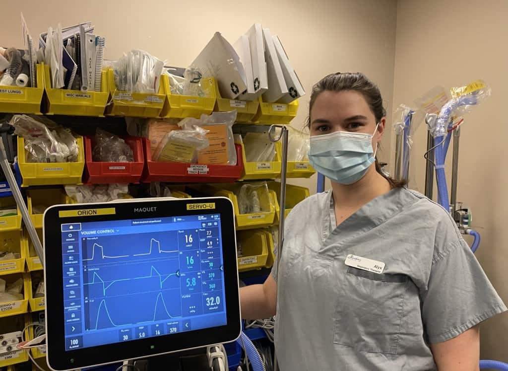 Image of Respiratory therapist Alyx, standing next to a machine