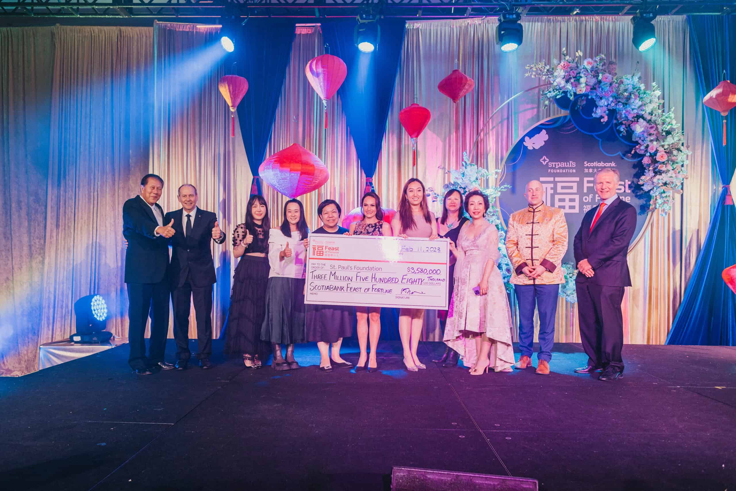 Photo shows people on stage at the Feast of Fortune gala, holding a large cheque