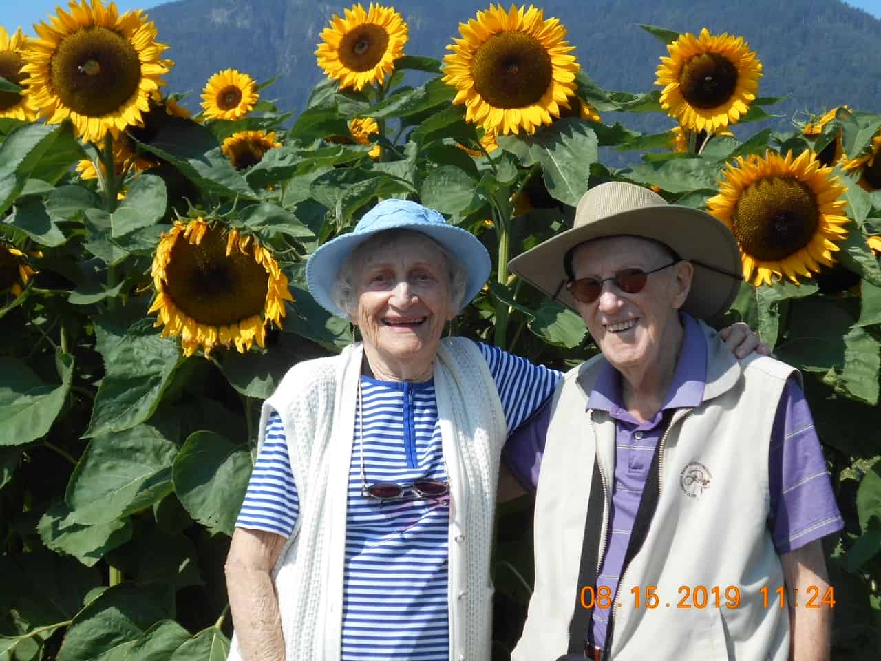 John and Evelyn Bell standing in front of sunflowers.