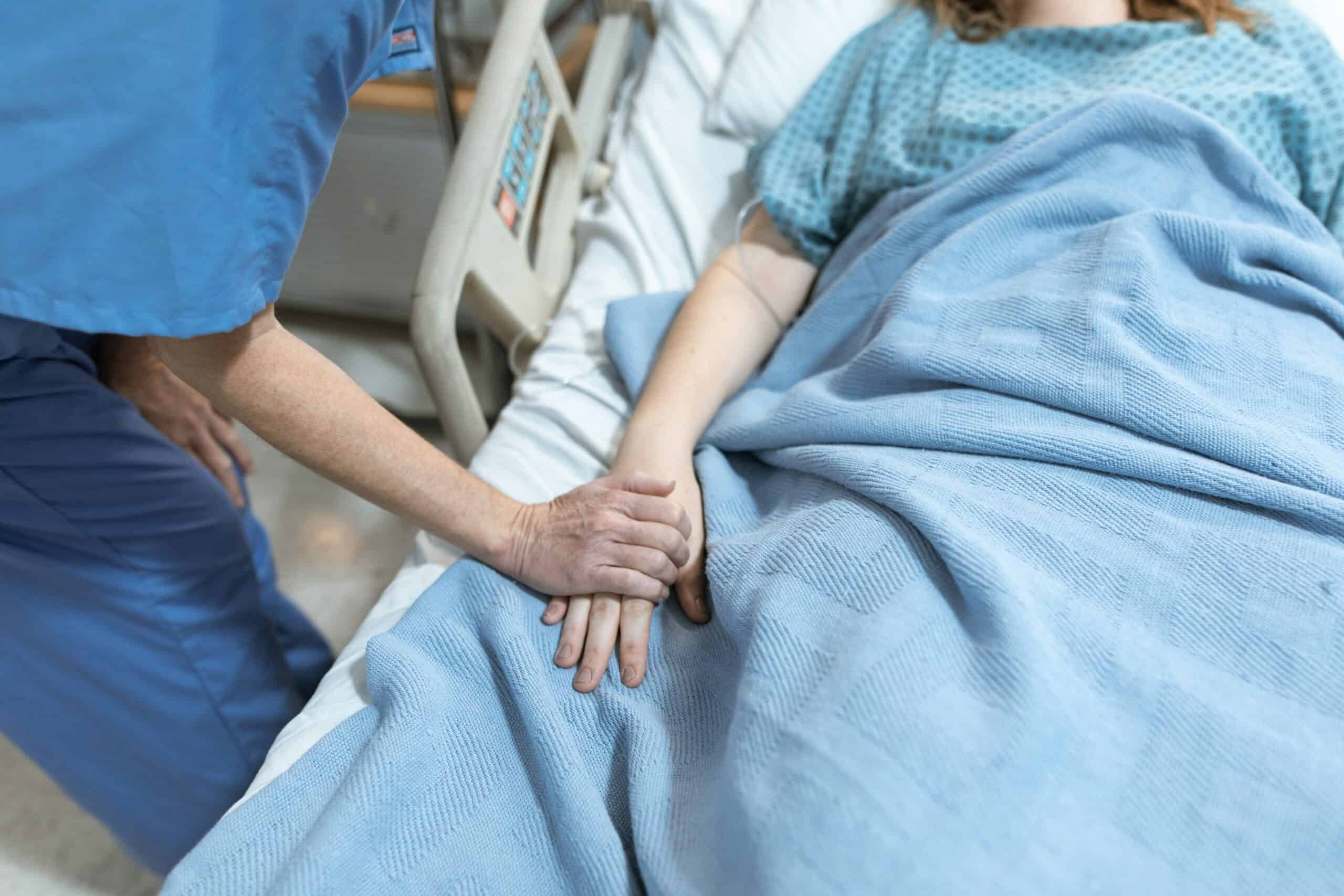 A nurse holding a patient's hand in the palliative care unit at St. Paul's Hospital