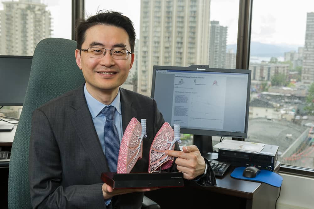 Dr. Don Sin in a suit holding and pointing to a model of a human lung..