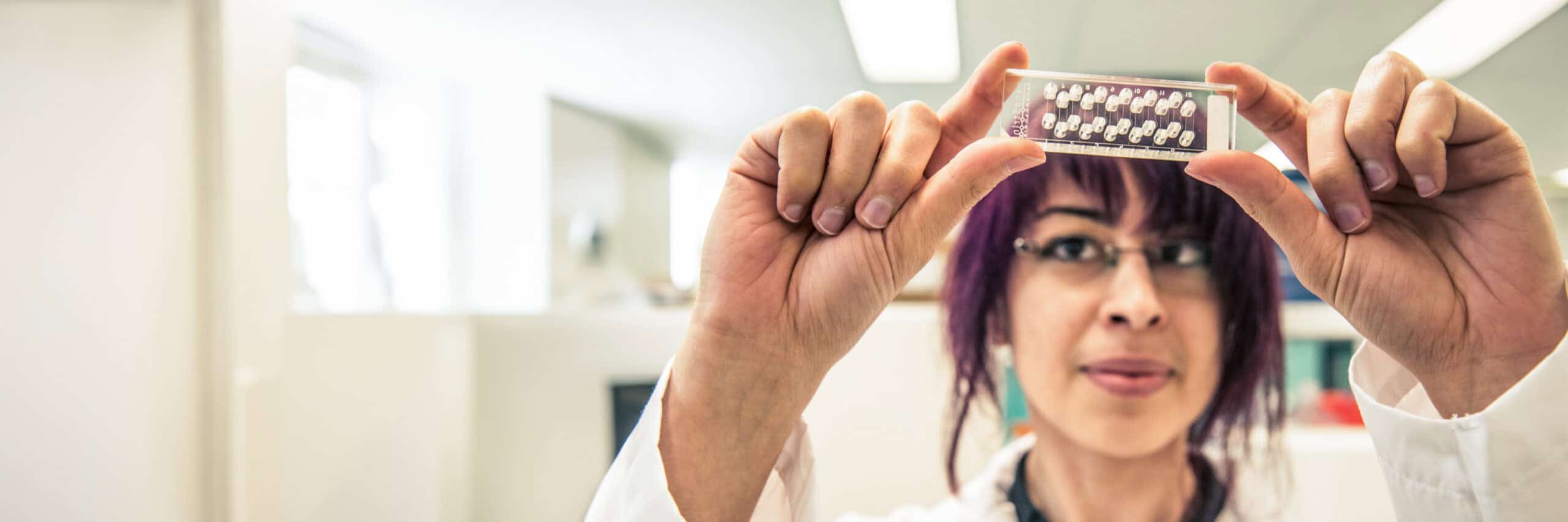 A health care member at St. Paul's Hospital holding up sample between her fingers and looking at it