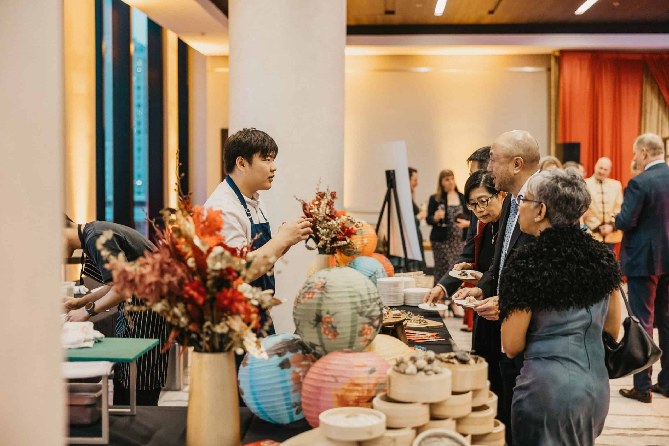 A chef at St. Paul's Foundation's 2024 Feast of Fortune gala explaining the featured food to guests standing at the food station.