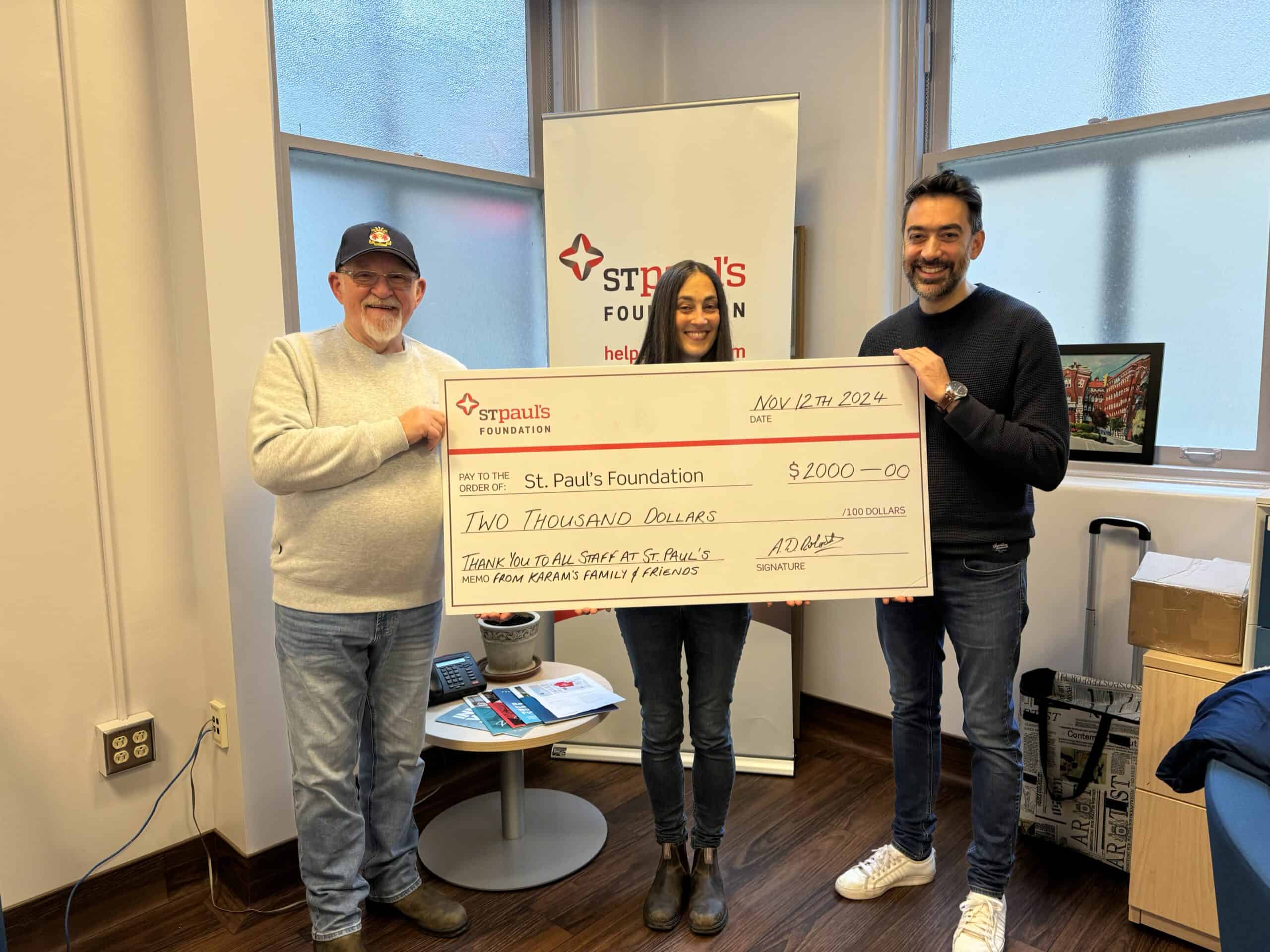 Three people holding a giant cheque donation.