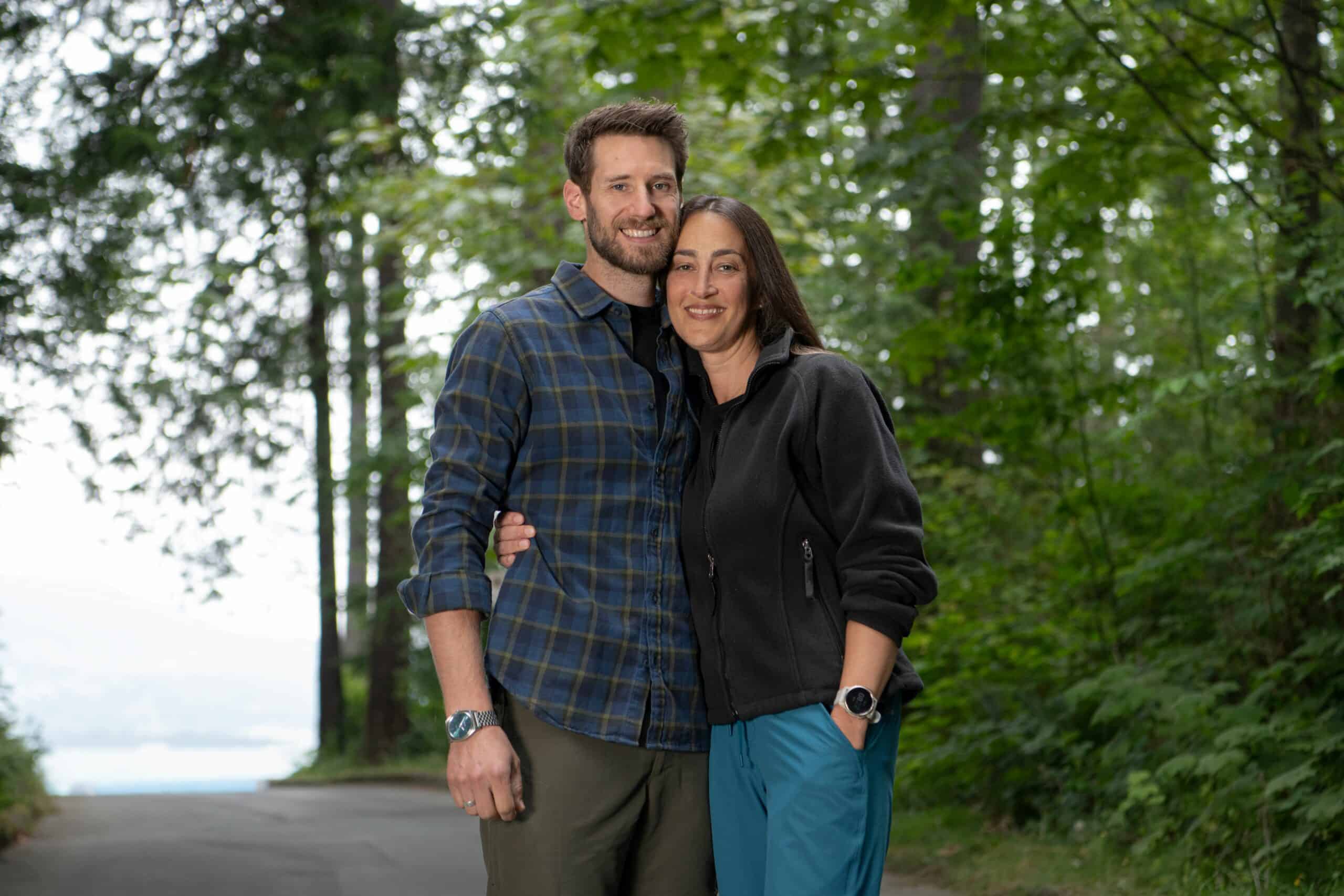 Matt and Karam, arms around one another, in front of trees and greenery