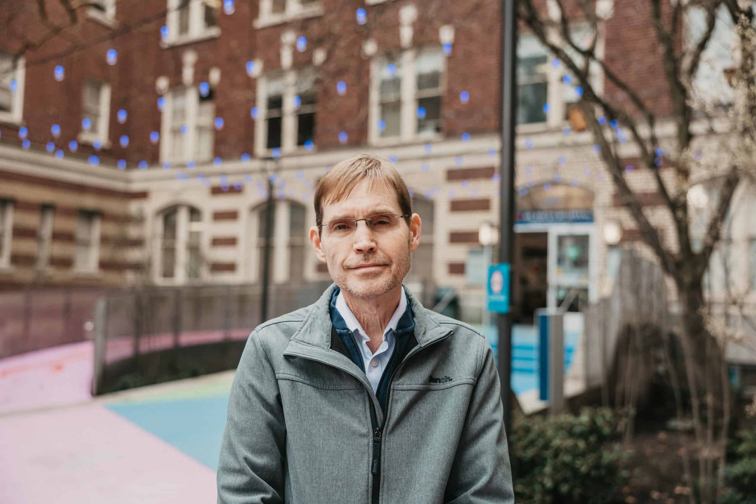 Keith Meldrum, stands outside St. Paul's Hospital, wearing a jacket.