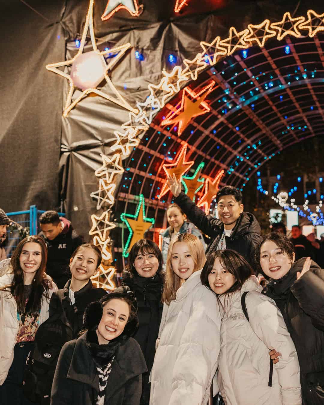 A group of smiling people standing outside St. Paul's Hospital's Lights of Hope lighting display.