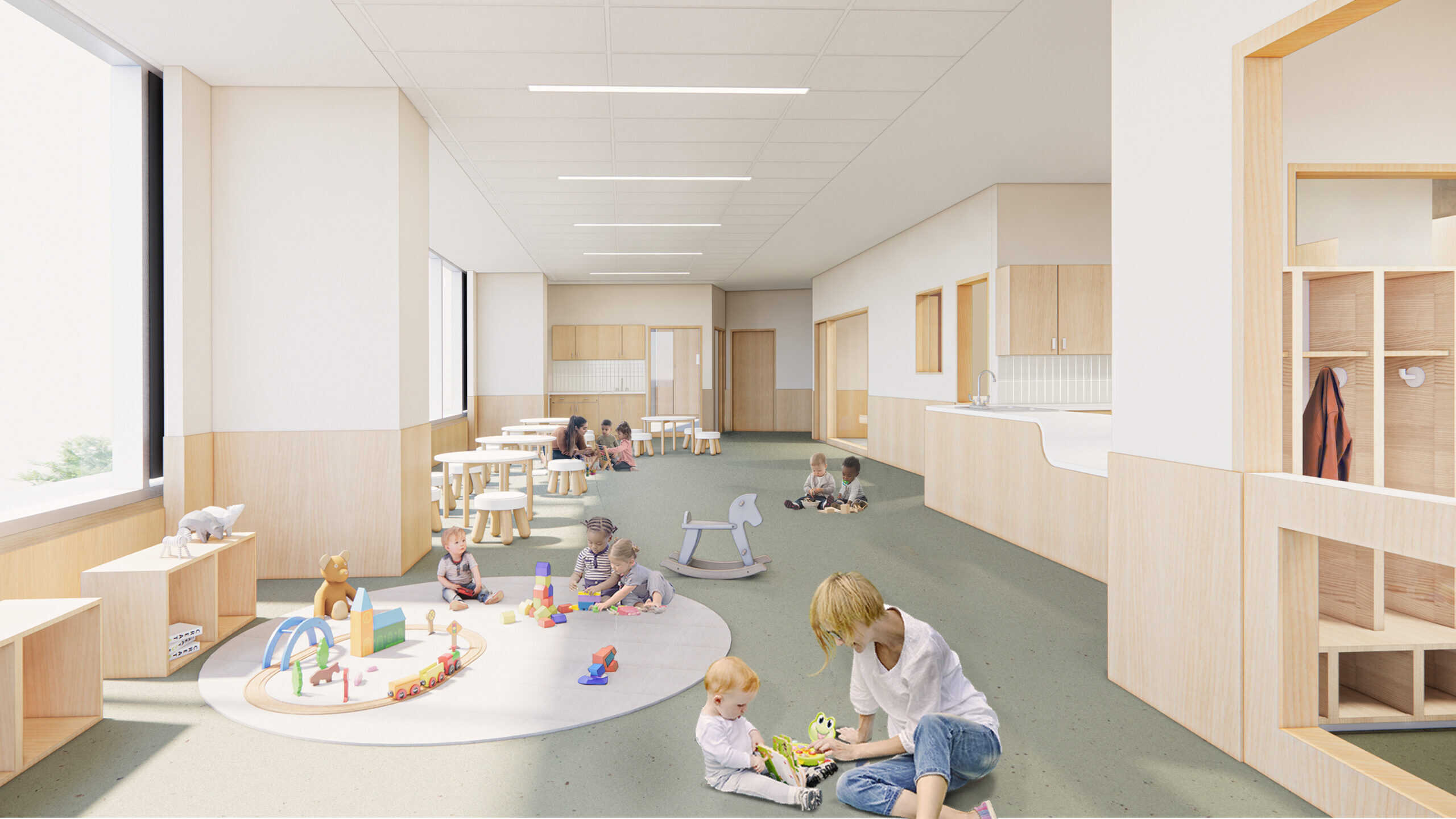 Children play with toys in a bright childcare room with tables, rugs, and large windows.