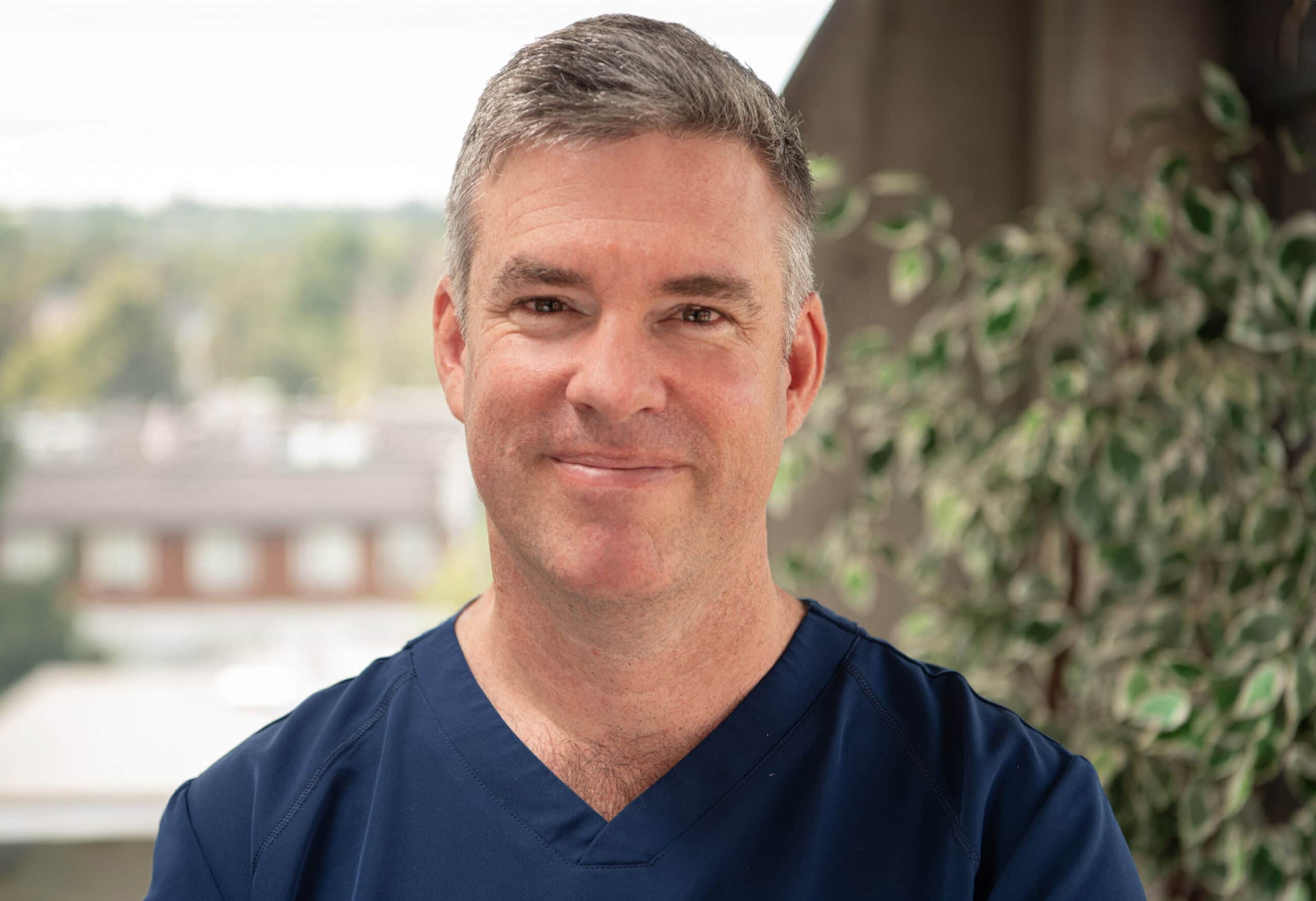 Dr. Greg Moloney, stands in front of a tree at Mount St. Joseph Hospital