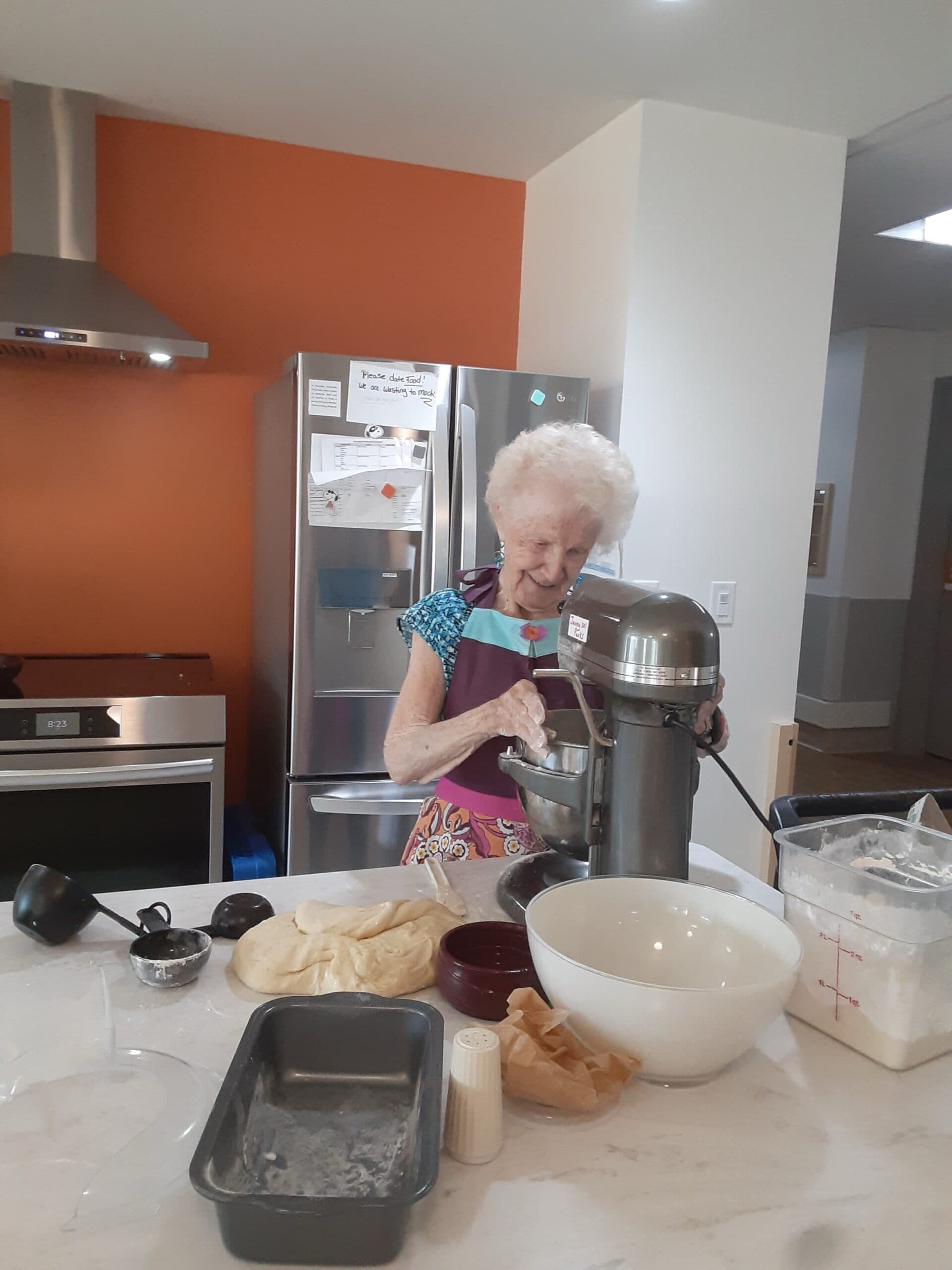 A resident baking and using a standup mixer in the kitchen at Providence Living at The Views