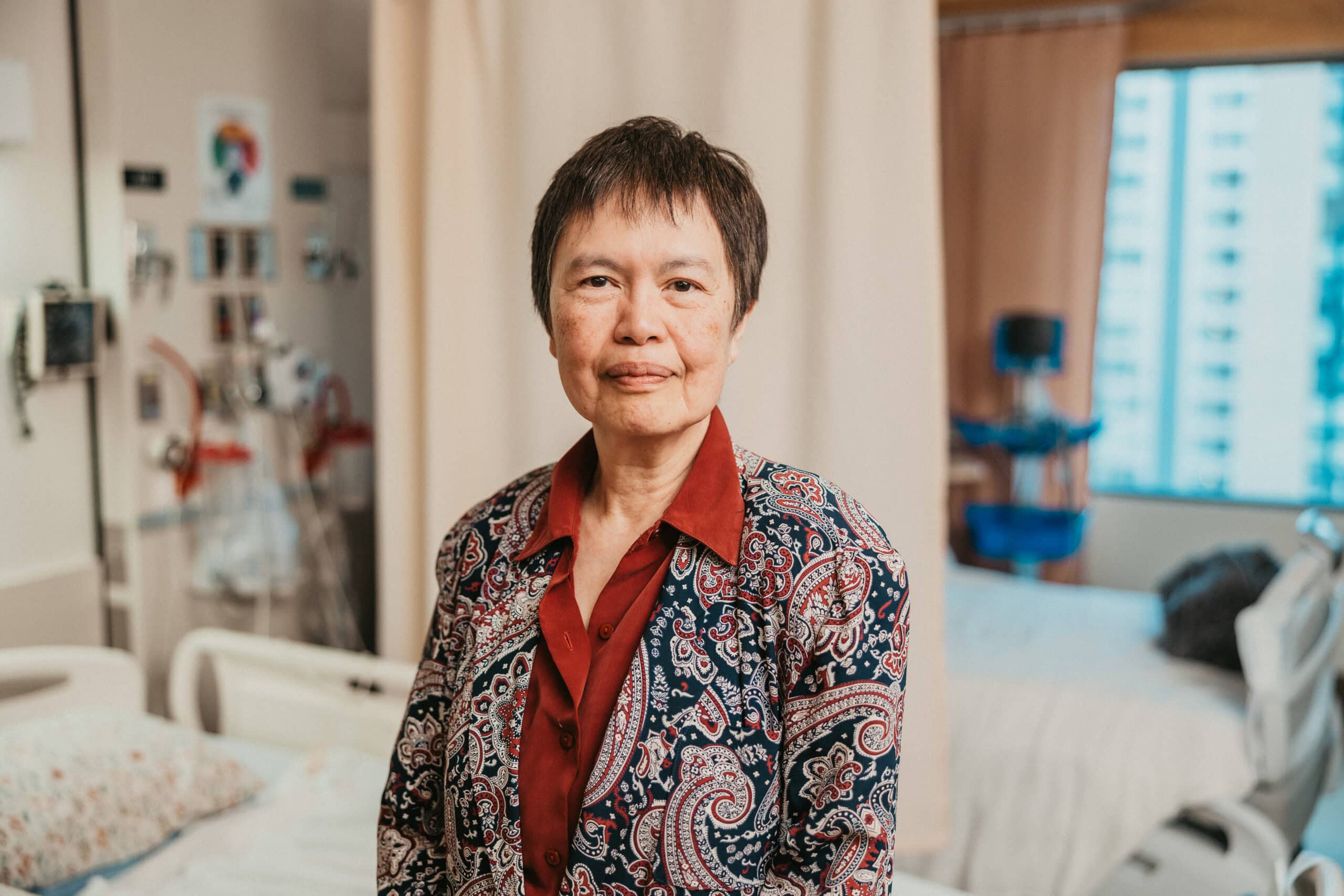 Dr. May Ong sits in a treatment room on a hospital bed at St. Paul's Hospital.