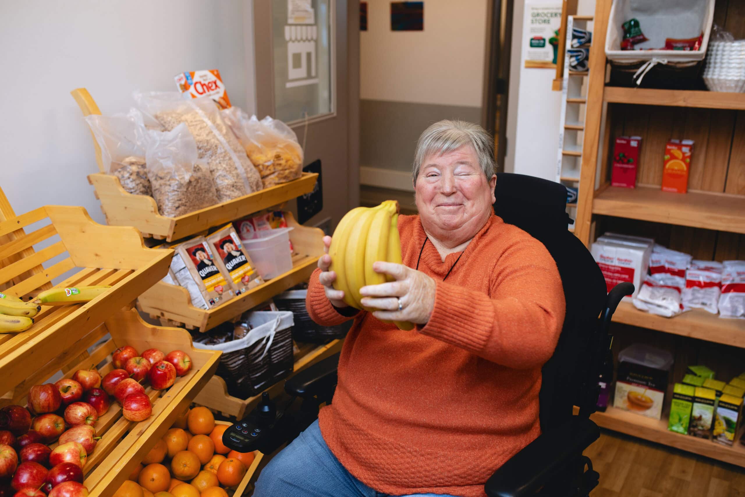 Jean holding a bunch of bananas in Providence Living and The Views’ onsite market, where residents can choose their own groceries.