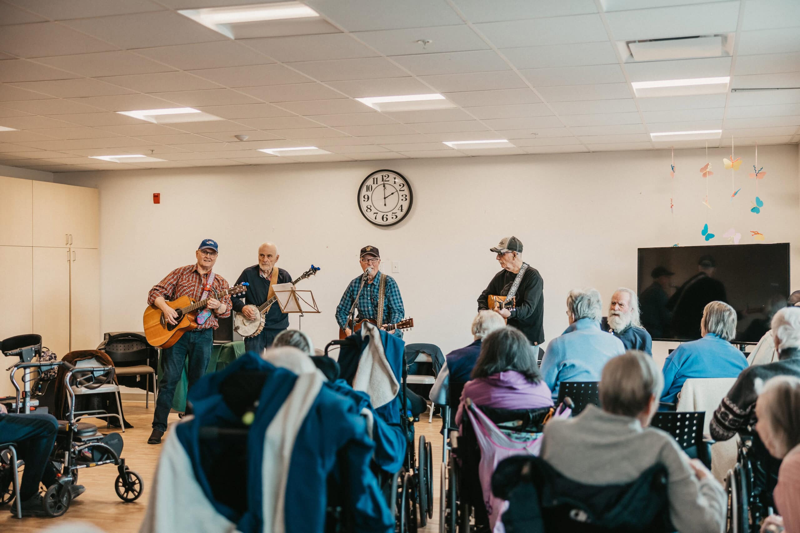 Four men stand, holding guitars, playing in front of a crowd at the Views.