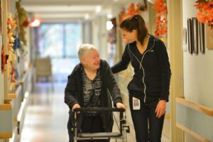 Woman with a walker walking with a Providence Health Care health care worker.